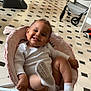 baby, child, smiling, sock, chair, indoor, floor, tiled_floor, furniture, baby_clothing, happy, person, infant, footwear, home, interior, seat, cute, relaxed, playful