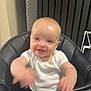 baby, child, high_chair, smile, happy, indoor, clothing, white_shirt, face, hands, waving, seat, black, furniture, background, dress, sparkly, human, infant, cute
