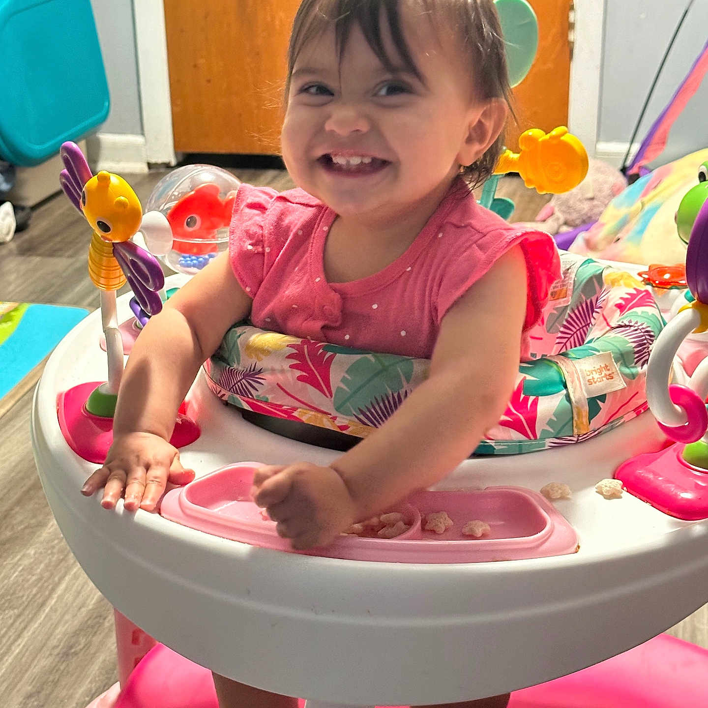 Savannah is registered to the contest to win money with this photo: baby, child, colorful, cute, door, expression, face, flooring, furniture, happy, home, indoor, person, pink_clothing, playful, smiling, toddler, toy, walker, young_child
