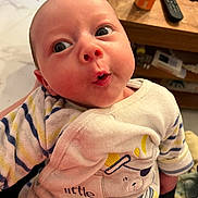 Sasha participe au concours pour gagner de l'argent avec cette photo : baby, infant, child, cute, surprised_expression, striped_clothing, bear_design, indoor, wooden_table, remote_control, can, person_holding, close_up, face, head, eyes, mouth, cozy, soft_fabric, human