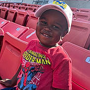 Kamden joined the competition — help win amazing prizes! child, boy, smiling, cap, tshirt, spiderman, stadium, seats, red, sunlight, outdoor, happy, casual_clothing, portrait, person, daylight, young, cheerful, leisure, seating