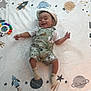 baby, smiling, hat, overalls, animal_print, blanket, space_theme, rocket, planet, stars, infant, cute, lying_down, child, playful, happy, socks, toddler, face, clothing