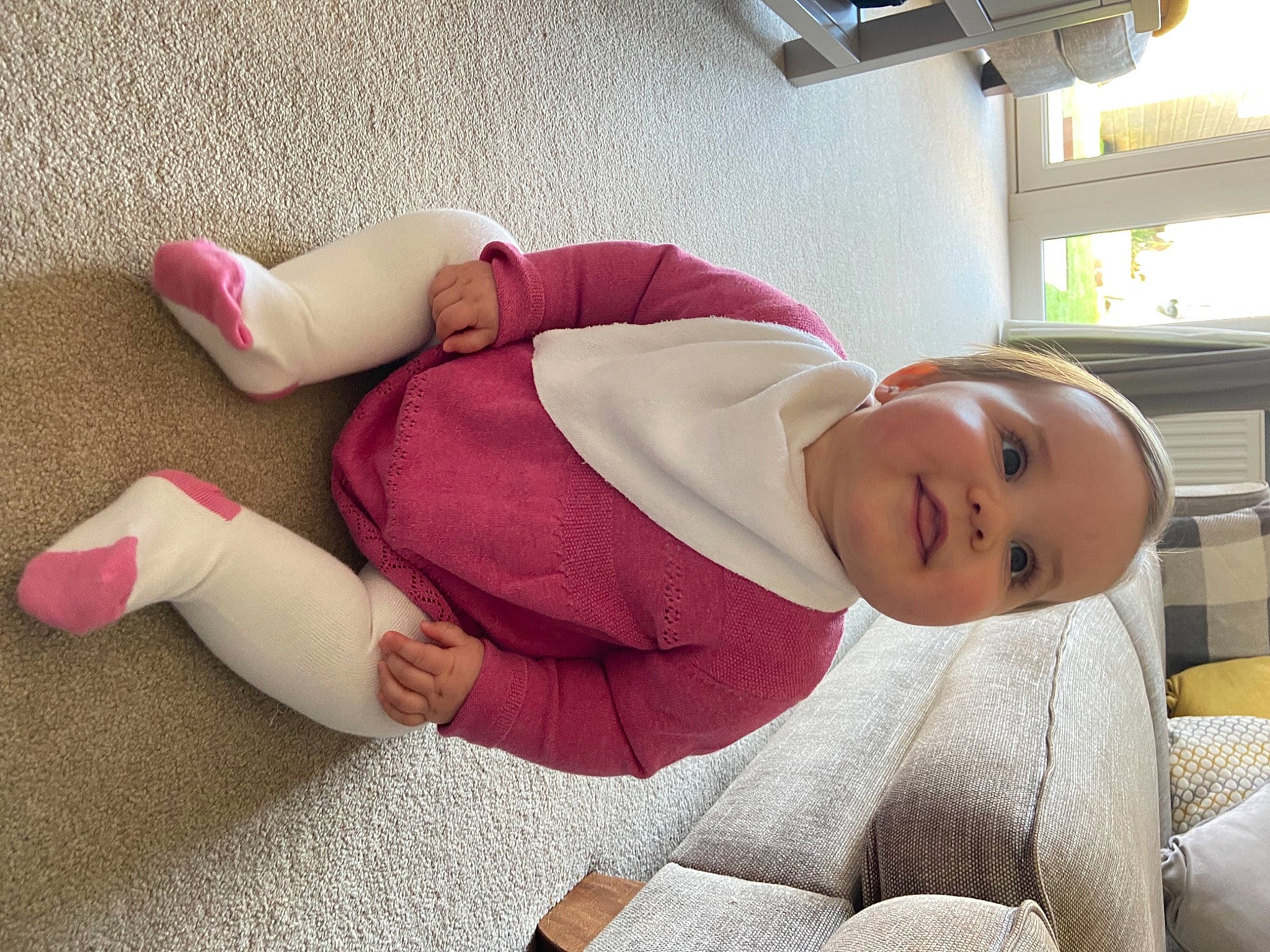 Darcie joined the competition — help win amazing prizes! baby, baby_toddler_clothing, comfort, couch, facial_expression, finger, hat, human_body, human_leg, knee, leg, linens, magenta, mammal, person, sitting, skin, smile, sock, thigh