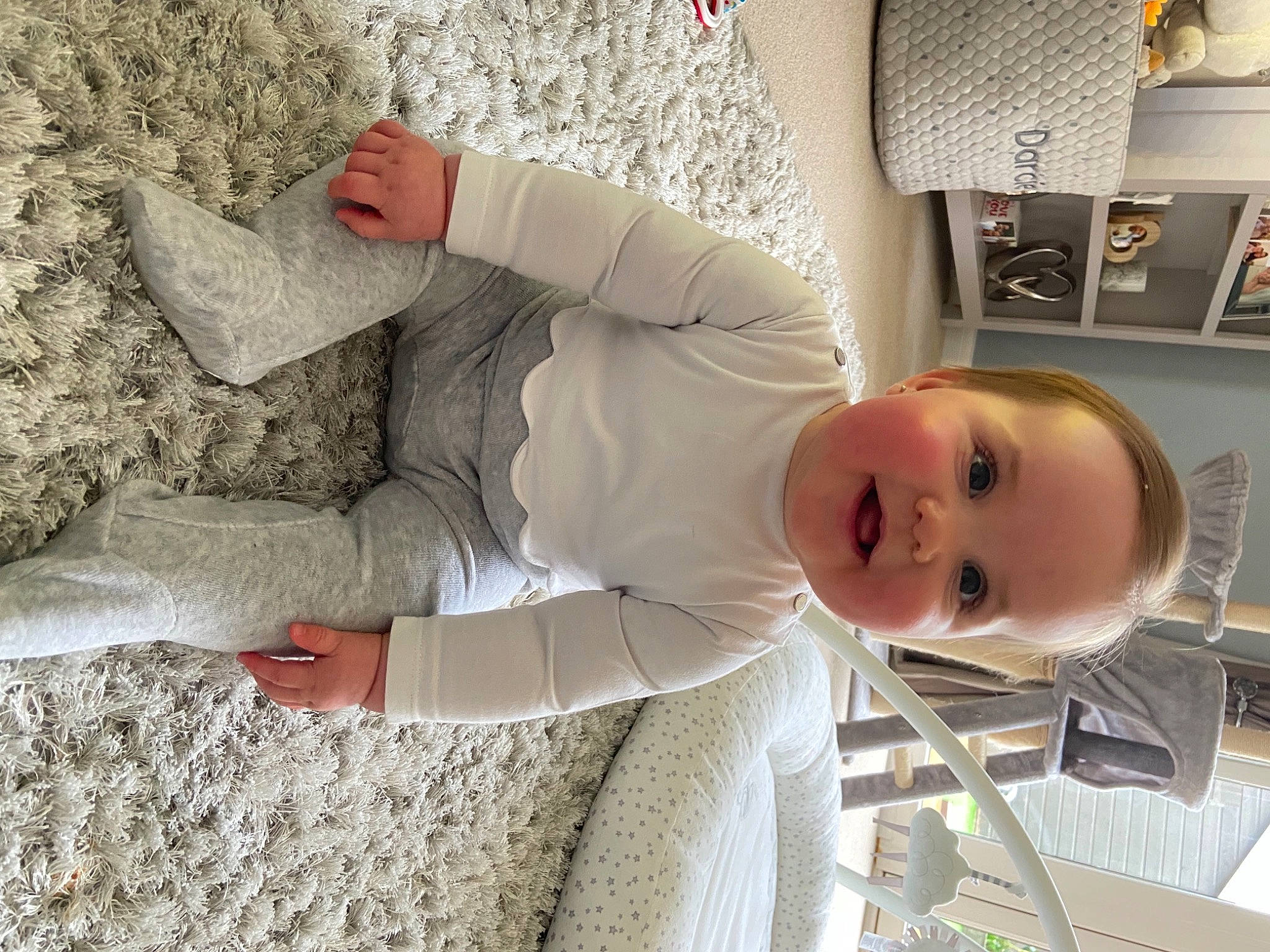 Darcie is registered to the contest to win money with this photo: baby, child, comfort, flooring, fur, hat, linens, mammal, person, room, shelf, shelving, sitting, sleeve, smile, stuffed_toy, suit, textile, toddler, toy