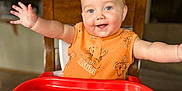 Elliott joined the competition — help win amazing prizes! baby, high_chair, smiling, orange_clothing, blue_eyes, arms_outstretched, red_tray, indoor, kitchen, wooden_chair, happy, infant, person, cute, child, portrait, home, seated, toddler, bright