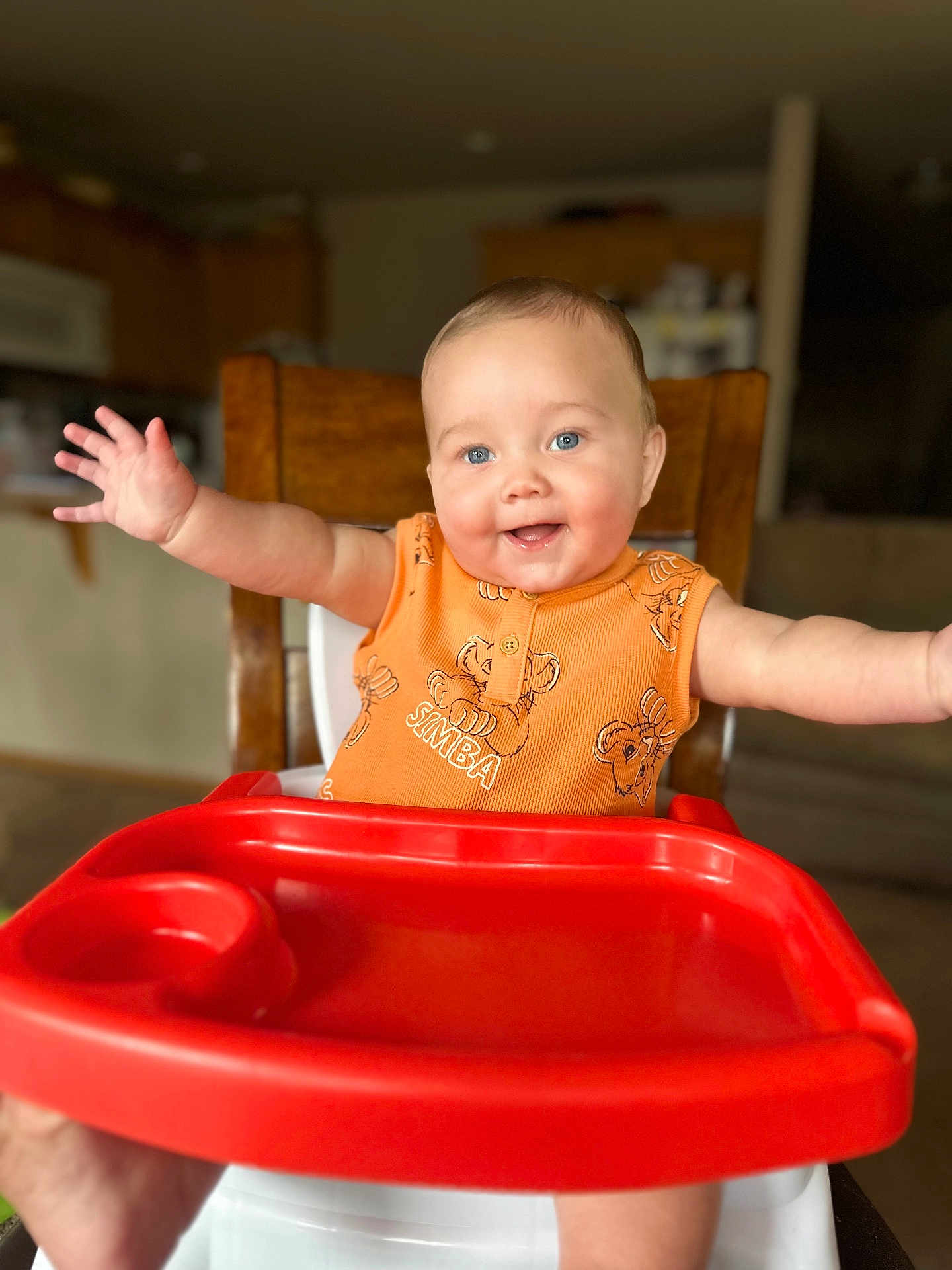 Elliott joined the competition — help win amazing prizes! baby, high_chair, smiling, orange_clothing, blue_eyes, arms_outstretched, red_tray, indoor, kitchen, wooden_chair, happy, infant, person, cute, child, portrait, home, seated, toddler, bright