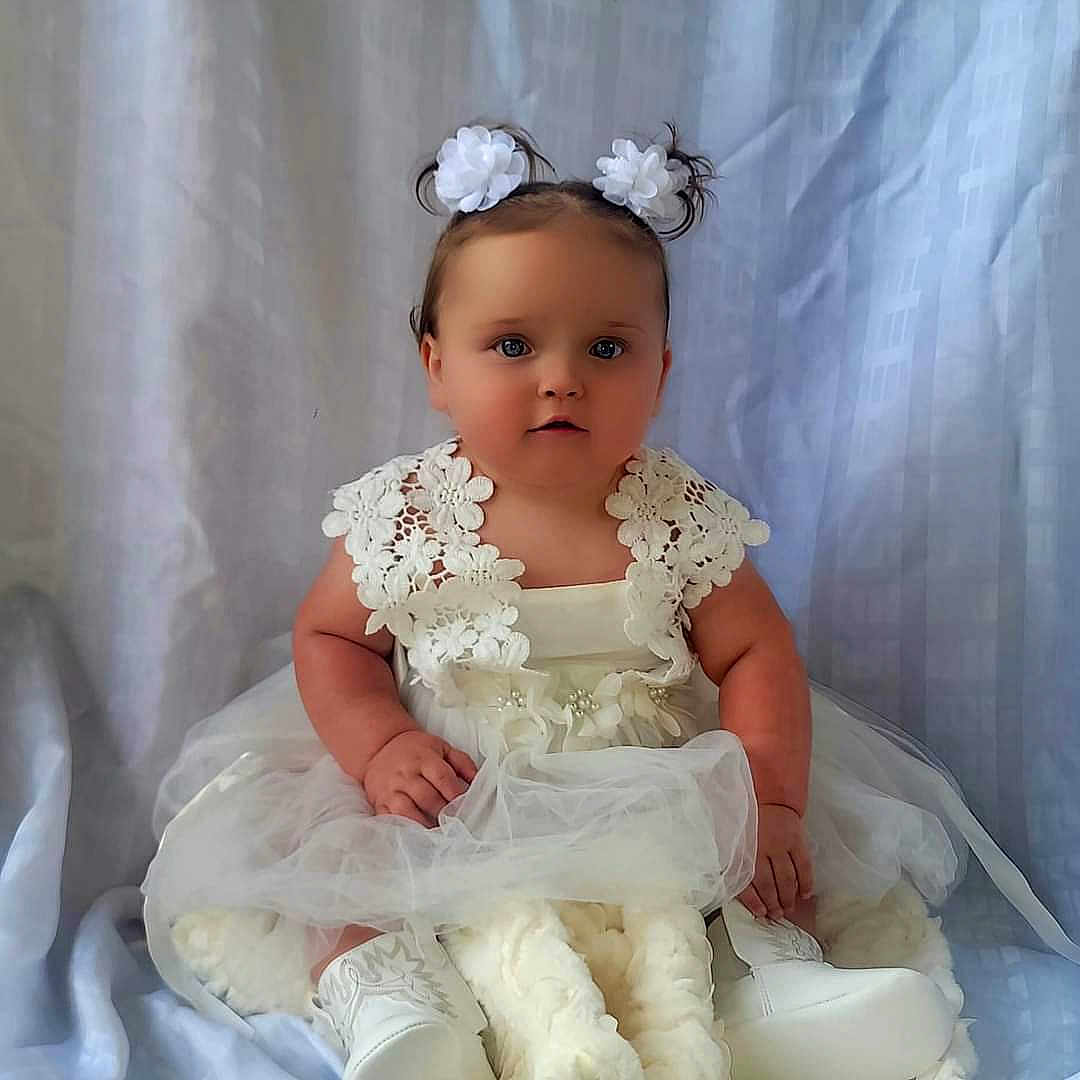 Baylee joined the competition — help win amazing prizes! baby, clothing, dress, face, fashion, flower, flowerarrangement, flowerbouquet, formalwear, gown, hair, head, pants, person, photography, plant, portrait, sitting, sleeve, toy