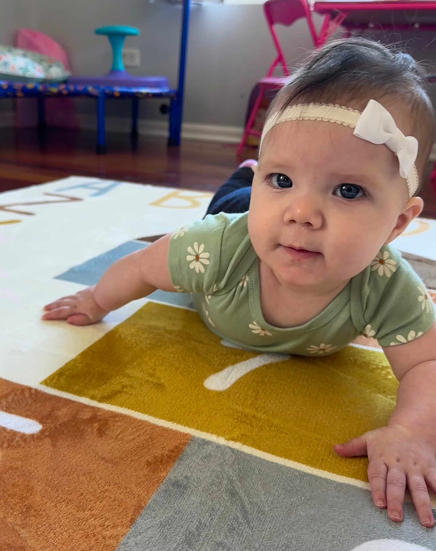 Tyler joined the competition — help win amazing prizes! baby, child, headband, blue_eyes, green_shirt, daisy_pattern, carpet, alphabet_rug, hand, floor, indoor, furniture, pink_chair, playroom, curious, portrait, tummy_time, infant, cute, home