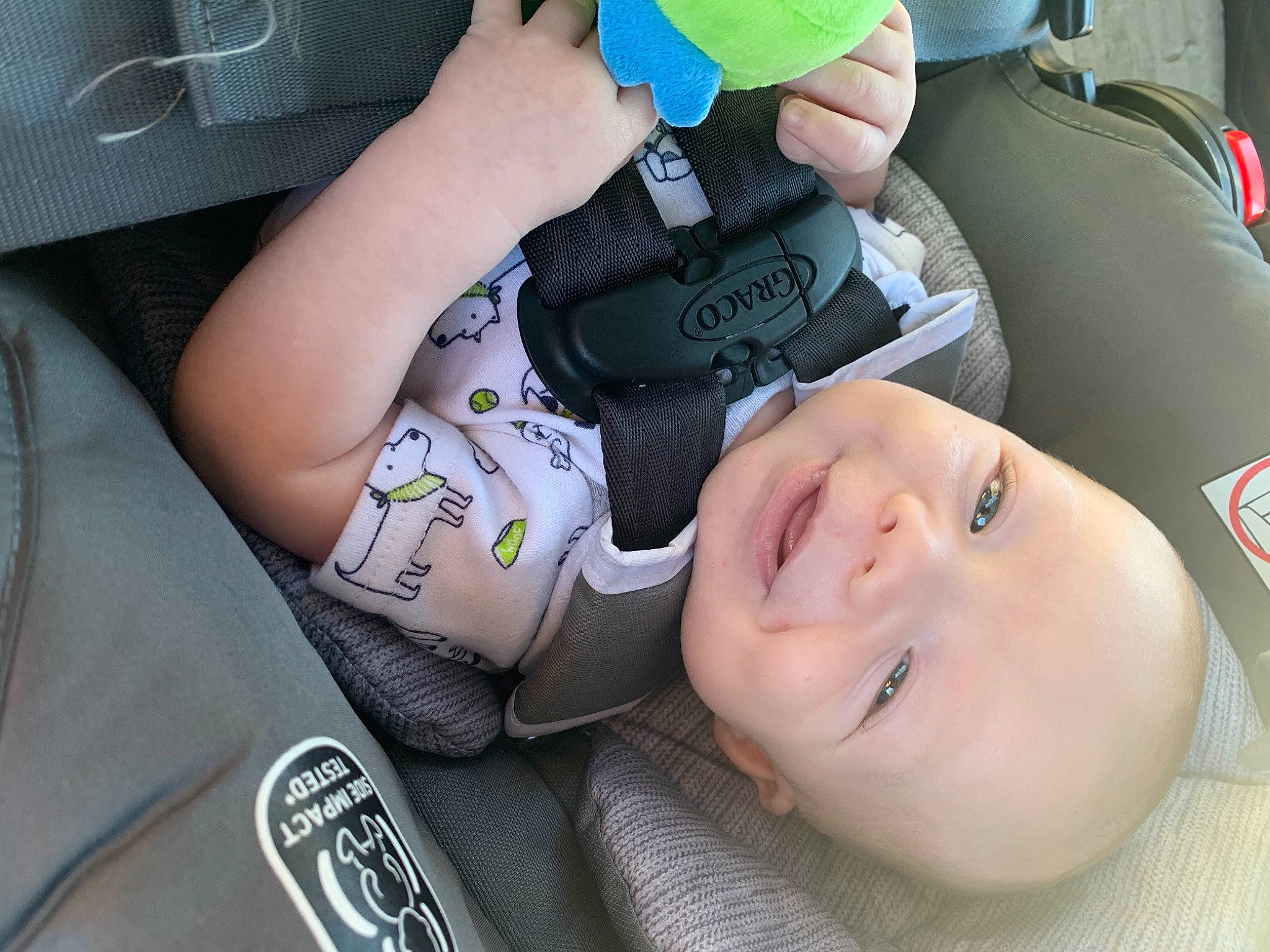 Colton is registered to the contest to win money with this photo: auto_part, baby, baby_laughing, baby_toddler_clothing, car_seat, cheek, child, comfort, cool, finger, gesture, grass, green, happy, human, mouth, person, product, skin, smile