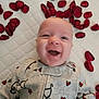arrows, baby, bedding, closeup, cute, face, heart_pattern, indoor, infant, joy, laughing, mattress, onesie, petals, portrait, quilt, red, rose_petals, smile, white_background