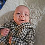adorable, baby, bed, bedding, blanket, buttoned_shirt, close_up, cozy, eyes, face, hand, infant, lying_down, mouth, newborn, patterned_fabric, plaid_shirt, portrait, quilt, smiling
