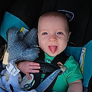 Nathan is registered to the contest to win money with this photo: baby, blanket, blue_eyes, car_seat, child, comfort, cute, elephant_toy, green_shirt, happy, indoors, infant, person, playful, safe, seatbelt, smiling, stuffed_animal, tongue_out, young_child