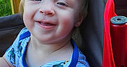 Nathan is registered to the contest to win money with this photo: toddler, child, smile, happy, outdoor, chair, red, blue_shirt, patterned_clothing, face, person, baby, cute, green_background, wooden_rail, portrait, sitting, daylight, young_child, casual