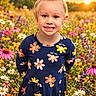 child, girl, portrait, smiling, sunset, flower_field, wildflowers, garden, outdoor, nature, dress, floral_pattern, blonde_hair, ponytail, happy, standing, sunlight, colorful, summer, daisy