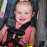 Isabella is registered to the contest to win money with this photo: baby, child, car_seat, smile, blue_eyes, pink_clothing, hair_clip, toy, safety_harness, infant, cute, happy, indoor, seat_belt, person, portrait, close_up, baby_toy, child_seat, pink