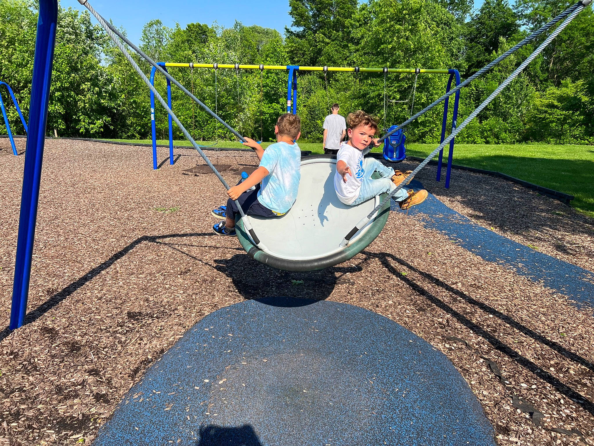 Xaiden is registered to the contest to win money with this photo: asphalt, blue, city, electric_blue, fun, grass, leisure, nonbuilding_structure, outdoor_play_equipment, people_in_nature, person, plant, play, playground, pole, recreation, shade, sky, soil, swing