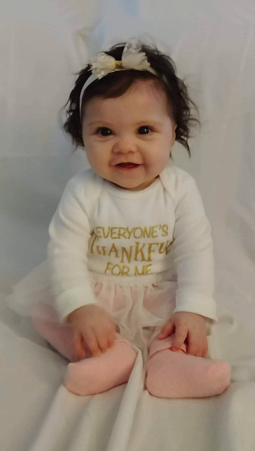 Elianna is registered to the contest to win money with this photo: baby, baby_toddler_clothing, cheek, child, child_model, comfort, eye, face, flash_photography, hairstyle, happy, human_leg, knee, person, photo_shoot, portrait_photography, sitting, sleeve, smile, thigh