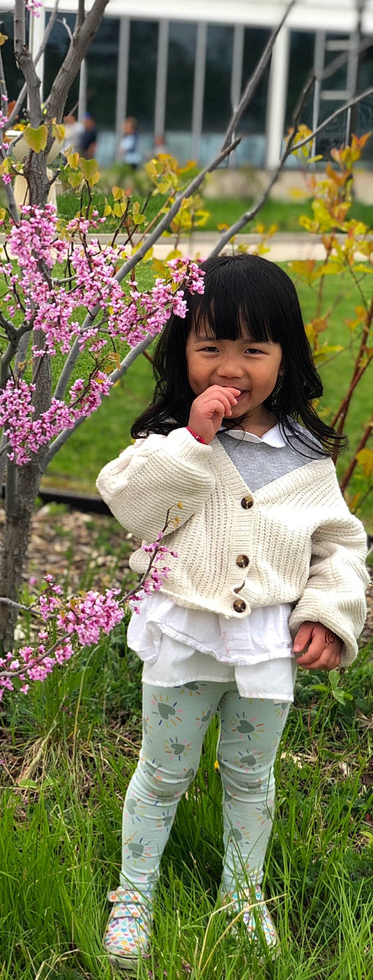 Kasia is registered to the contest to win money with this photo: baby_toddler_clothing, bangs, beauty, blossom, botany, brown_hair, child, facial_expression, flower, grass, hair, hairstyle, happy, pattern, people_in_nature, person, petal, pink, plant, sleeve