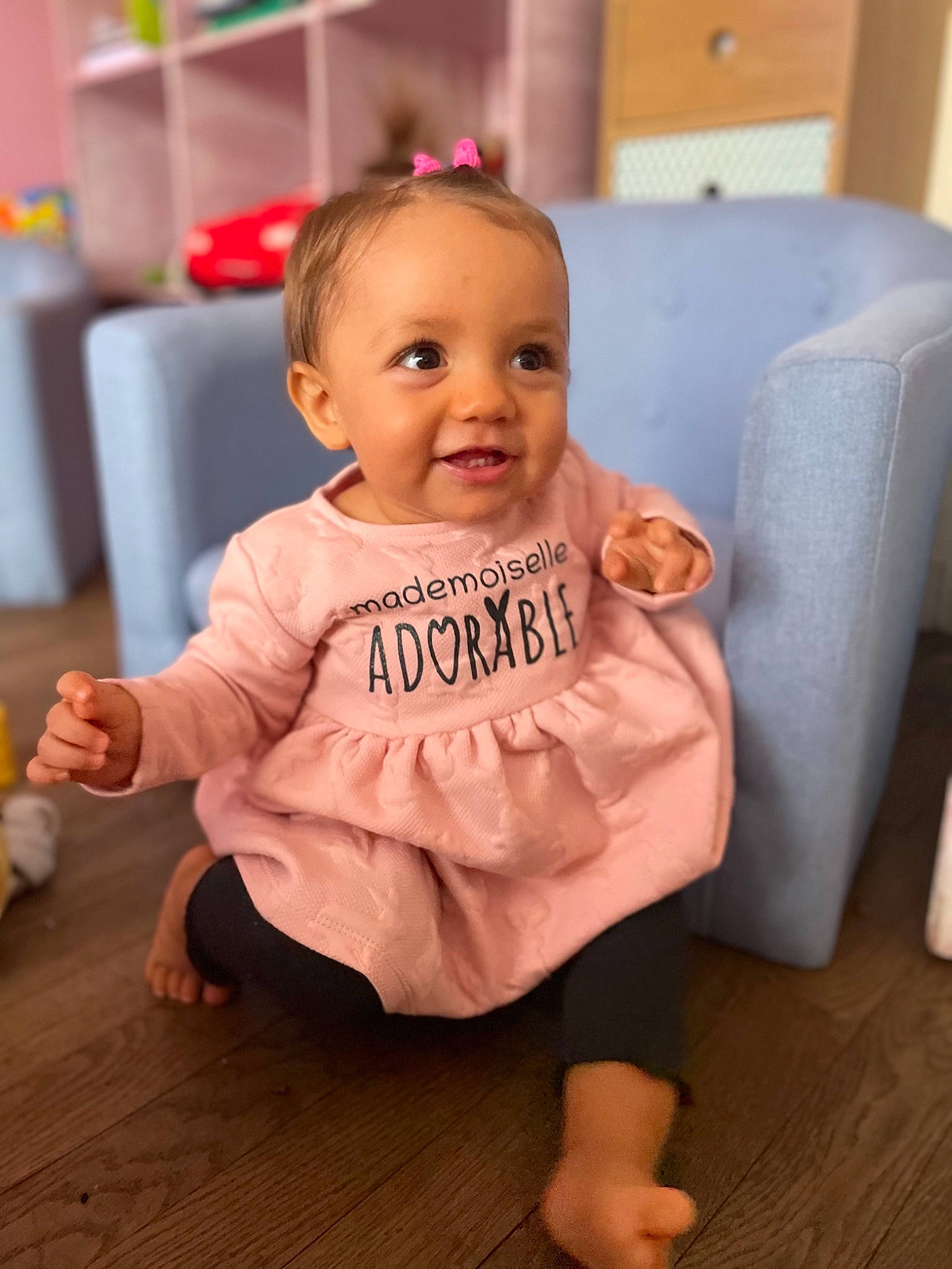 Mya a rejoint le concours — aidez-le/la à gagner de superbes lots ! baby, baby_toddler_clothing, cheek, child, floor, flooring, foot, fun, happy, hardwood, head, iris, joy, person, pink, sitting, skin, sleeve, smile, thumb