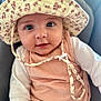 baby, infant, hat, floral_hat, cute, portrait, face, eyes, smile, clothing, peach_outfit, white_sleeves, child, young_child, indoors, soft_light, close_up, headwear, baby_girl, seated