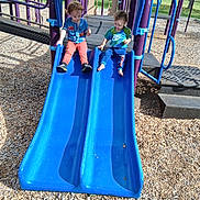 Jordan is registered to the contest to win money with this photo: children, toddler, playground, slide, outdoor, park, siblings, sitting, play_structure, blue_slide, sunlight, wood_chips, summer, clothing, smiling, childhood, recreation, playtime,  안전한, photography