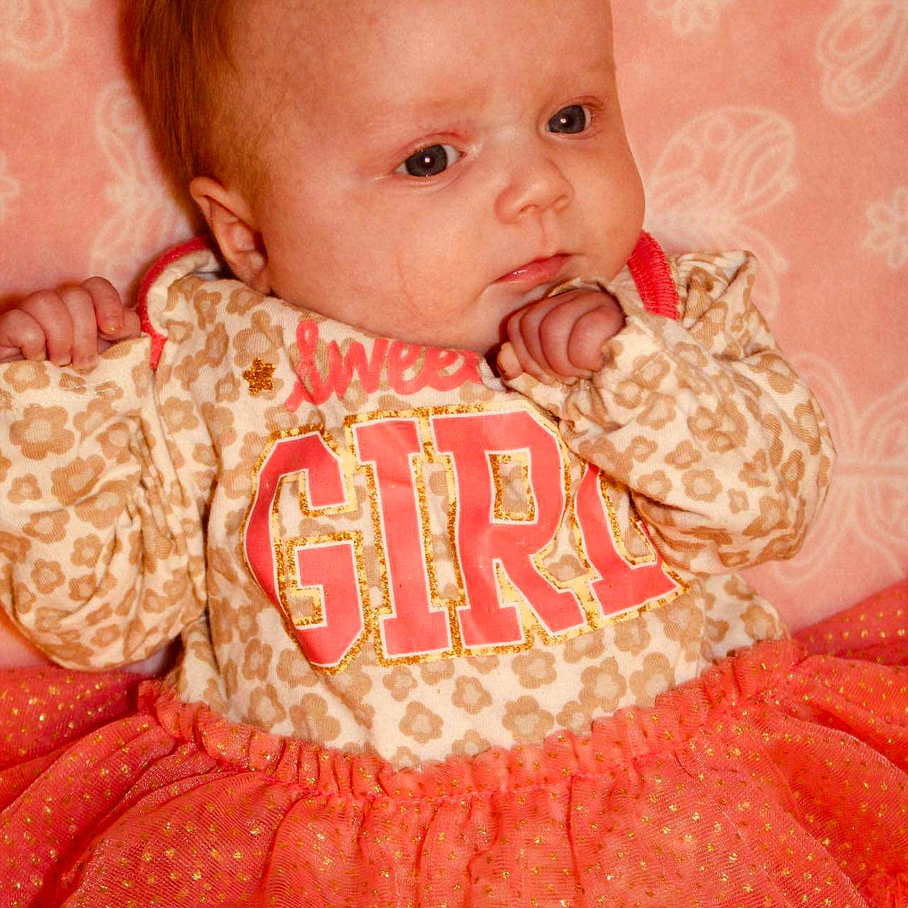 Lacey is registered to the contest to win money with this photo: baby, bodypart, clothing, couch, dress, face, finger, furniture, hand, happy, head, laughing, newborn, person, photography, portrait, quilt, sitting, sleeping, smile