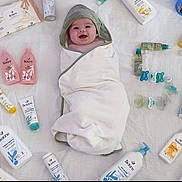 Gino a rejoint le concours — aidez-le/la à gagner de superbes lots ! baby, smiling, towel, hood, white_sheet, baby_care_products, bottles, tubes, pacifiers, skincare, cream, lotion, baby_bath, infant, happy, wrapped, cute, product_arrangement, biolane, soft