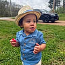 toddler, child, hat, straw_hat, blue_shirt, shorts, grass, outdoor, daytime, vehicle, black_suv, food, holding, nature, trees, cloudy_sky, road, person, cute, summer_clothing