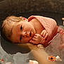 baby, newborn, infant, wrapped, pink_cloth, metal_tub, water, floating_flowers, flower_petals, peaceful, portrait, closeup, skin, hands, head, young_child, soft_lighting, indoors, serene, gentle