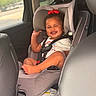 baby, car_seat, child, clothing, cute, foot, hair, hand, happy, head, portrait, red_bow, safety, seatbelt, sitting, skin, smiling, toddler, vehicle_interior, window