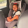 baby, car_interior, car_seat, child, child_safety, clothing, cute, earrings, happy, infant, portrait, red_bow, safety_harness, seat, seatbelt, smiling, sunlight, toddler, travel, window