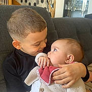 Cataléya a rejoint le concours — aidez-le/la à gagner de superbes lots ! child, baby, sibling, siblings, brother, cuddling, hug, couch, living_room, wallpaper, knit_cardigan, bib, hand, haircut, portrait, smile, gaze, indoor, cozy, furniture