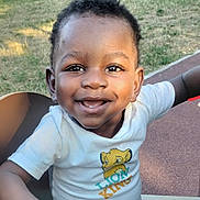 éliel participe au concours pour gagner de l'argent avec cette photo : toddler, child, smiling, outdoor, grass, bench, lion_king, tshirt, happy, face, person, park, daylight, cute, joyful, short_hair, skin, casual_clothing, nature, playground