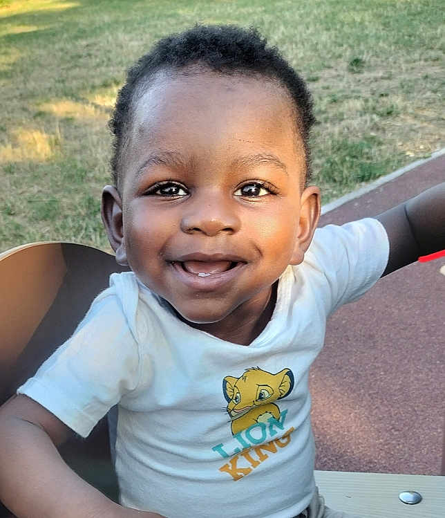 éliel participe au concours pour gagner de l'argent avec cette photo : toddler, child, smiling, outdoor, grass, bench, lion_king, tshirt, happy, face, person, park, daylight, cute, joyful, short_hair, skin, casual_clothing, nature, playground