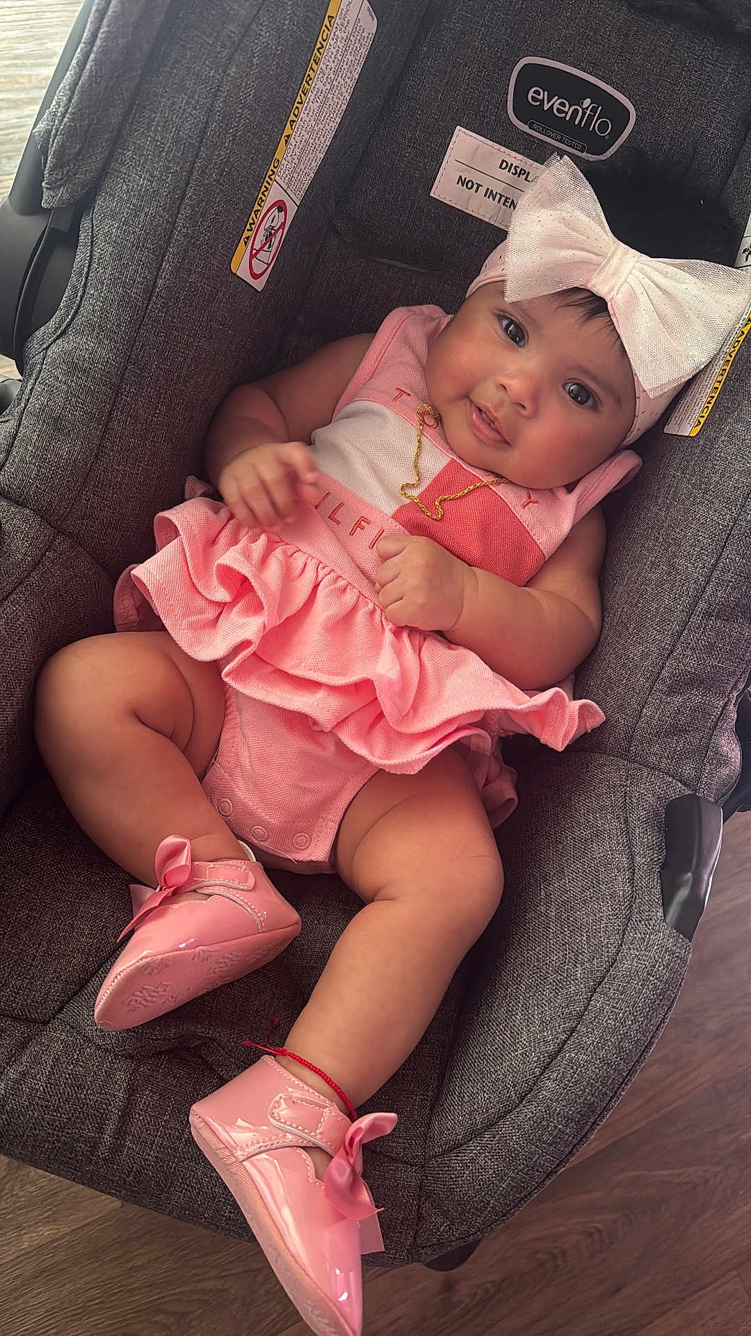 Samary is registered to the contest to win money with this photo: accessory, baby, bow, car_seat, child, clothing, cute, floor, footwear, gold_necklace, gray_car_seat, headband, indoors, infant, person, pink_dress, pink_shoes, portrait, sitting, smiling