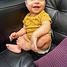 Santiago is registered to the contest to win money with this photo: baby, black_leather_couch, child, comfortable, cute, expression, face, feet, hands, happy, human, indoor, infant, portrait, purple_cushion, sitting, skin, smiling, toddler, yellow_onesie