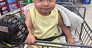 Santiago joined the competition — help win amazing prizes! aisle, baby, black_strap, blanket, child, drink_cans, expression, face, footwear_absent, grocery_store, hand, indoor, person, retail, shelf, shopping_cart, sitting, supermarket, toddler, yellow_clothing