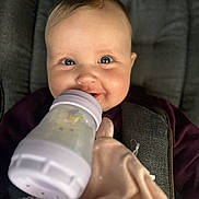 Giulia a rejoint le concours — aidez-le/la à gagner de superbes lots ! baby, bottle, blanket, child, cushion, face, feeding, infant, person, portrait, seat, smile, soft_toy, toddler, warm_clothing, young_child, indoors, closeup, happy, cute