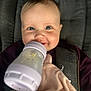 baby, bottle, blanket, child, cushion, face, feeding, infant, person, portrait, seat, smile, soft_toy, toddler, warm_clothing, young_child, indoors, closeup, happy, cute