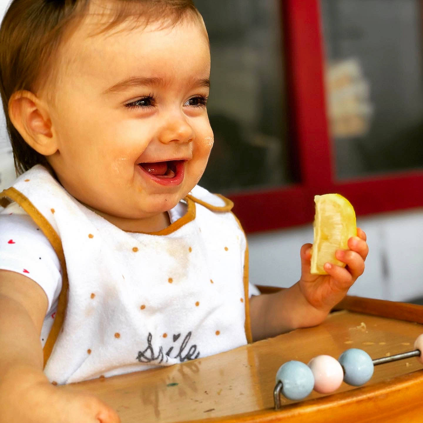 Romy participe au concours pour gagner de l'argent avec cette photo : baby, baby_toddler_clothing, child, chin, dress, finger, food, food_craving, hand, happy, indoor_games_and_sports, joy, nose, person, sleeve, smile, t_shirt, table, tableware, thumb