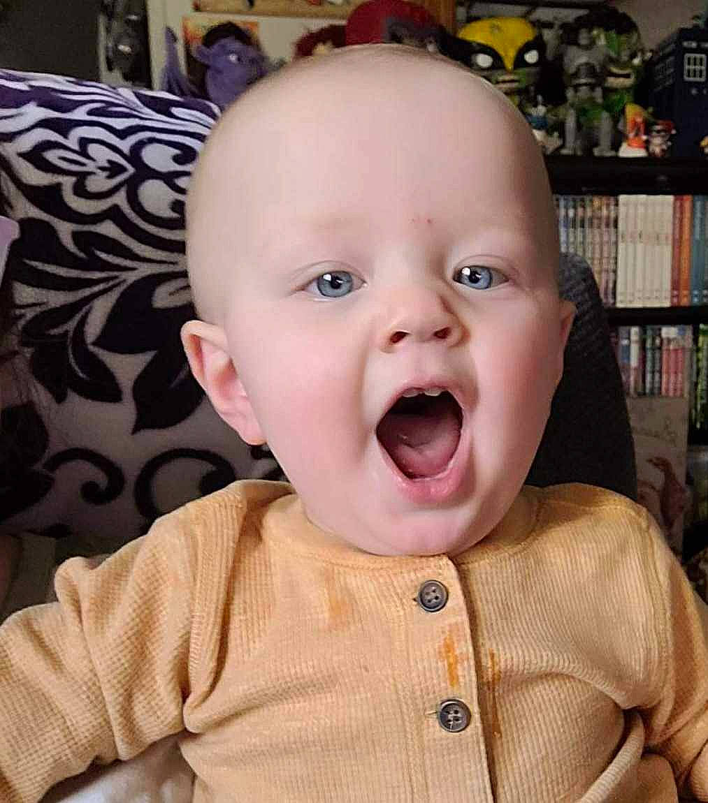Adam is registered to the contest to win money with this photo: baby, baby_toddler_clothing, cheek, chin, ear, eye, eyebrow, eyelash, forehead, fun, happy, iris, lip, mouth, nose, person, shelf, skin, sleeve, surprise