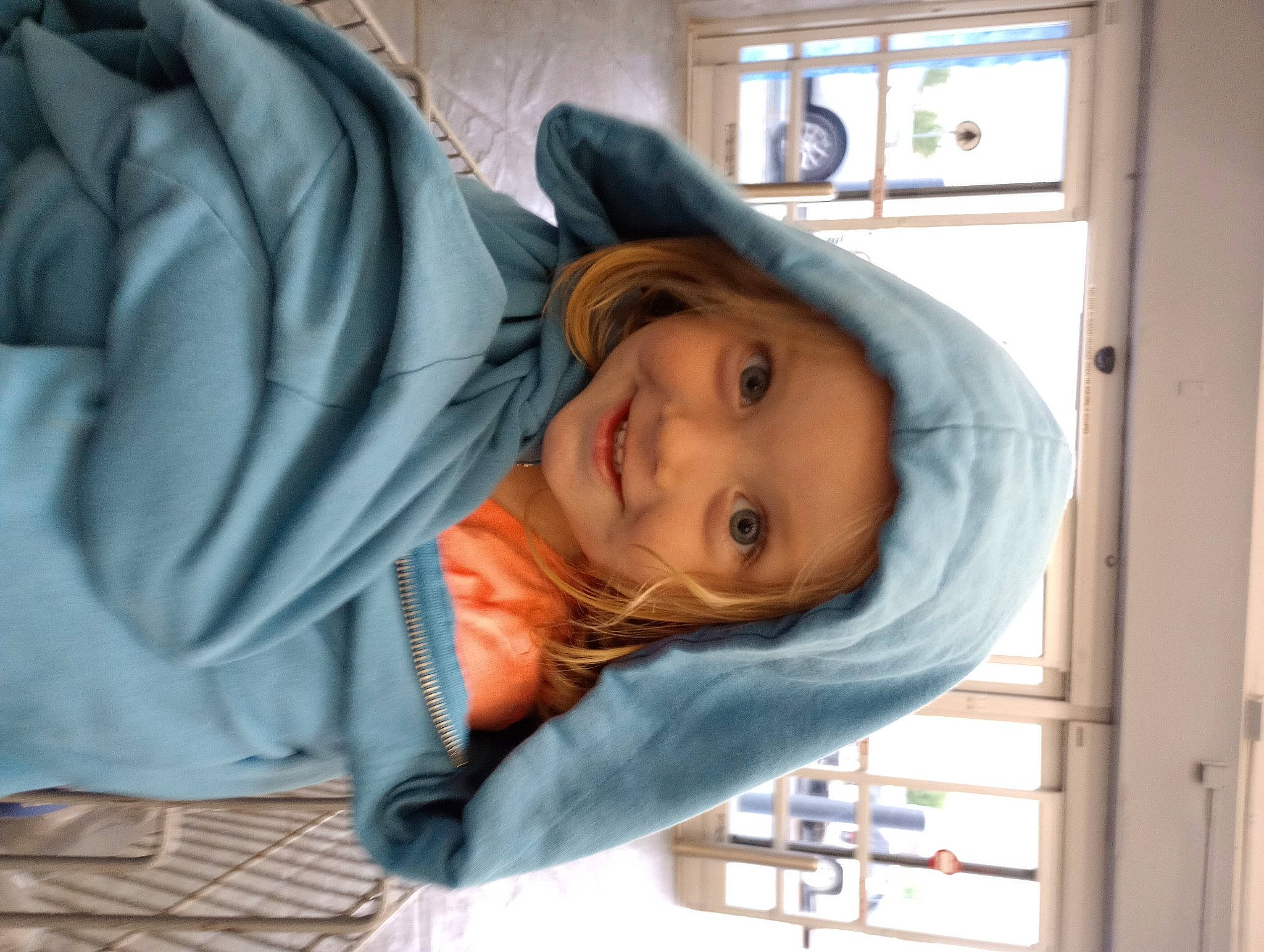 Annie Oaklee is registered to the contest to win money with this photo: cheek, child, comfort, electric_blue, eyebrow, fun, happy, headwear, hoodie, jacket, joy, leisure, nose, outerwear, person, room, sitting, smile, toddler, tree