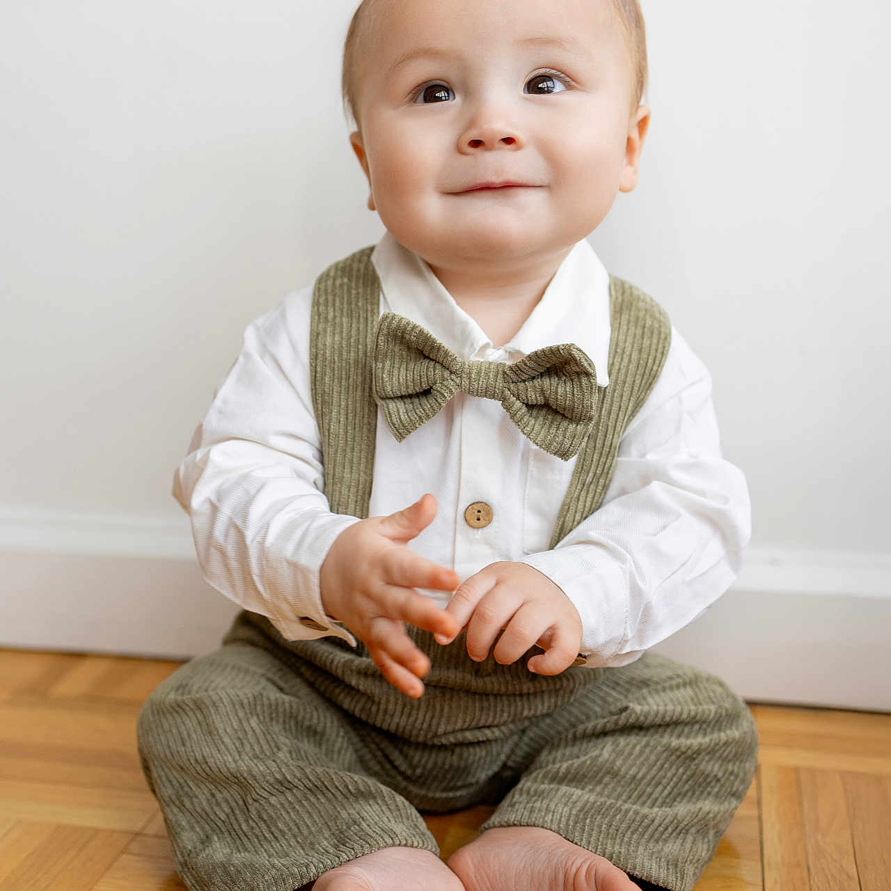 Emmett joined the competition — help win amazing prizes! baby, barefoot, bow_tie, child, corduroy, cute, eyes, face, floor, hands, happy, indoors, infant, person, portrait, sitting, smiling, white_shirt, wooden_floor, young_child