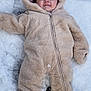 baby, child, snow, winter, onesie, fur, hood, smile, face, cute, cold, outdoor, footwear, clothing, person, infant, warm, frozen, nature, lying