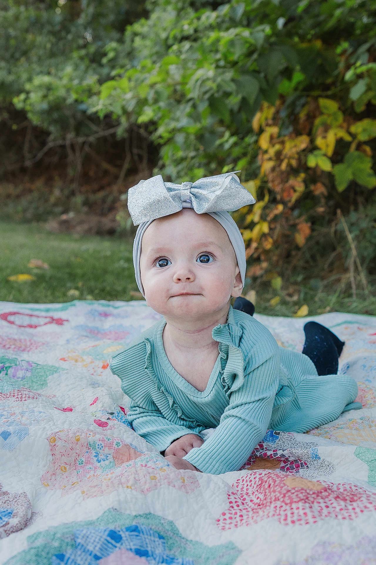 Athena joined the competition — help win amazing prizes! baby, child, outdoor, quilt, greenery, headband, bow, clothing, infant, grass, portrait, cute, smiling, toddler, nature, fabric, baby_girl, colorful, sitting, happy