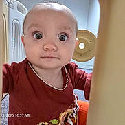 Athena is registered to the contest to win money with this photo: baby, barrier, candid, child, closeup, curious, expression, face, floor, head, indoor, maroon_clothing, orange_pants, peek, play_area, portrait, soft_lighting, toy, wide_eyes, young_child