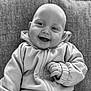 baby, smiling, hoodie, couch, happy, infant, portrait, black_and_white, seated, child, clothing, cozy, cute, face, expression, indoor, person, texture, young, casual