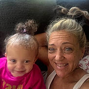 Luna joined the competition — help win amazing prizes! woman, toddler, child, smile, happy, indoors, selfie, curly_hair, blonde_hair, casual_clothing, pink_shirt, white_tank_top, couch, face, portrait, family, light, background, closeup, people