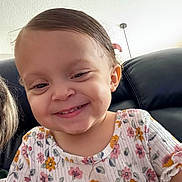 Luna is registered to the contest to win money with this photo: toddler, child, smiling, happy, face, hair, floral_shirt, clothing, indoor, couch, leather, person, portrait, cute, young_child, sitting, skin, head, eyes, mouth