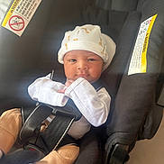 Danny is registered to the contest to win money with this photo: baby, infant, car_seat, hat, mittens, straps, warning_label, child, cute, newborn, clothing, seat, safety, indoors, person, portrait, young, resting, baby_clothes, closeup